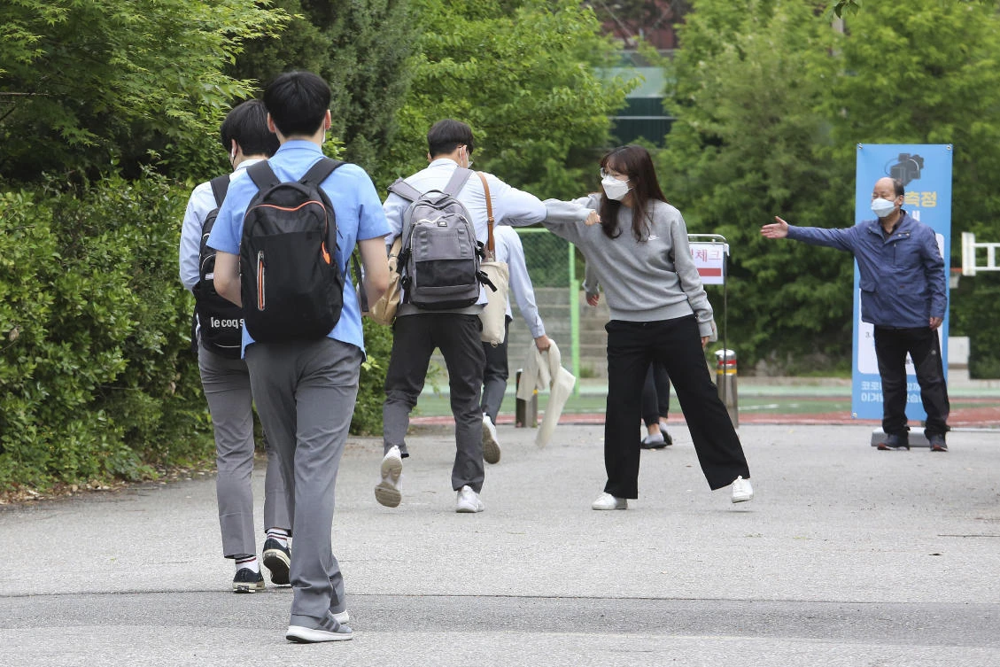 Above, a senior student is greeted by a teacher, second from right, upon his arrival at the Kyungbock High School in Seoul, South Korea on May 20, 2020. (AP)