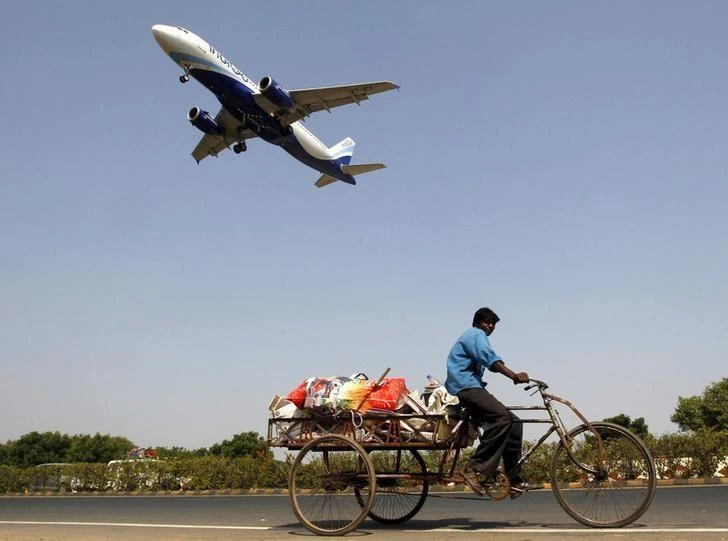 An IndiGo Airlines aircraft prepares to land as a man paddles his cycle rickshaw in Ahmedabad, India, October 26, 2015. (Reuters)