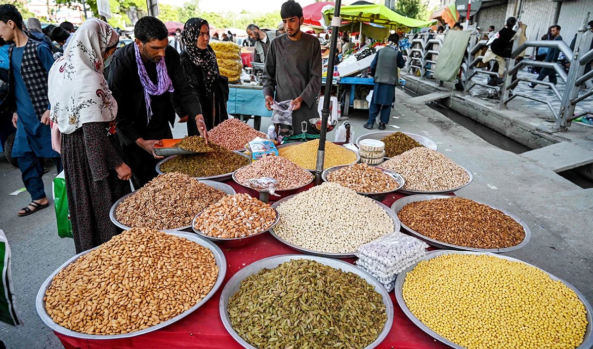 Customers choose dried lentils sold by a vendor at a roadside stall ahead of the Eid Al-Fitr festival which marks the end of the holy month of Ramadan, in Kabul. (AFP)