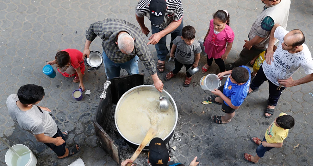 A Palestinian distributes hot wheat soup and porridge to poor residents before they break their fast in Gaza city. (AP)