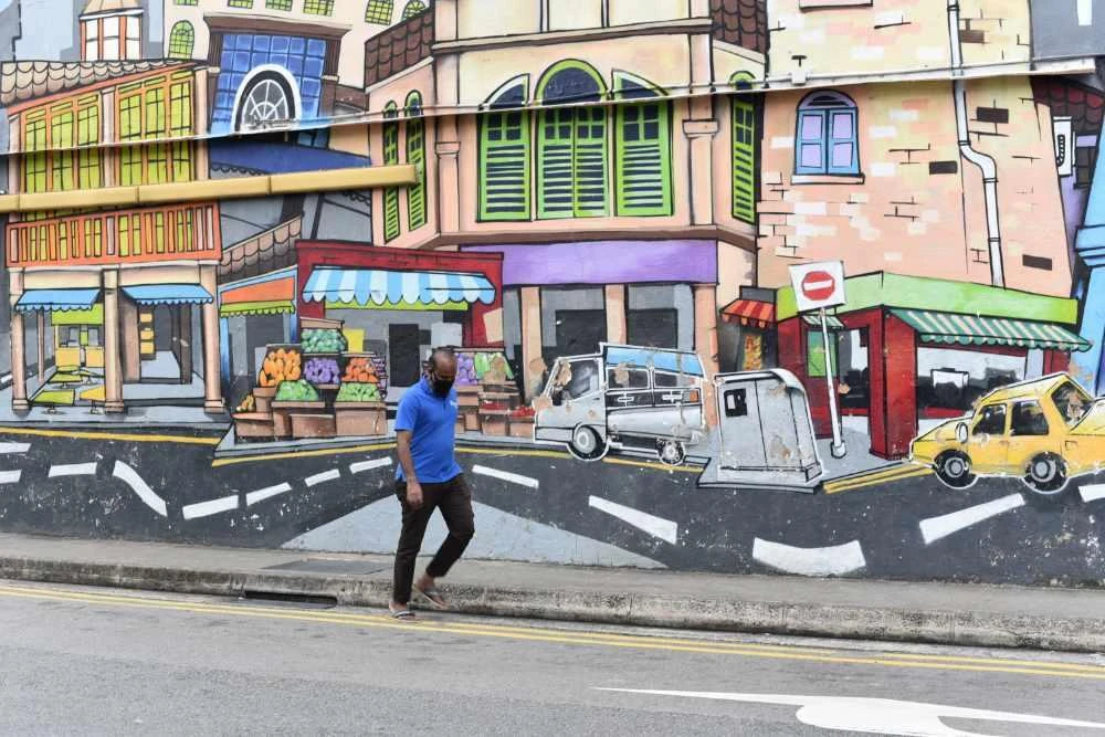 In this May 16, 2020, file photo, a passerby with a face mask walks past a wall mural in Singapore's Little India district on Saturday, May 16, 2020. Singapore has sentenced a drug suspect to death on the popular video chat app Zoom because of the city-state's coronavirus lockdown.(AP Photo/YK Chan, File)