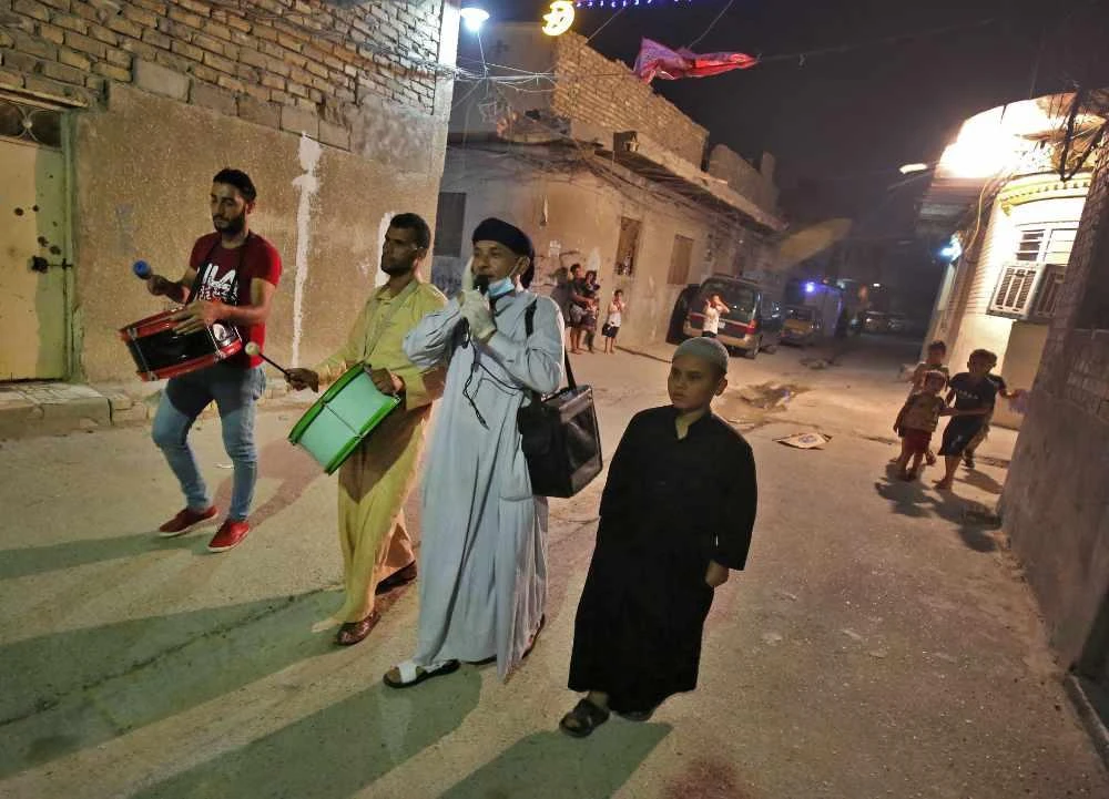 In this file photo taken on May 7, 2020 Sayyed Mozahem (2-R) the "Musaharati" calls for Muslims to have their final meal before a new day of fasting begins with the sunrise, in a small neighbourhood of the Iraqi capital Baghdad. (AFP / AHMAD AL-RUBAYE)