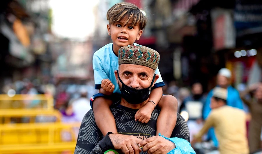 A man carries his son on his shoulders on the last Friday of Ramadan in the old quarters of New Delhi after the government eased restrictions imposed as a preventive measure against the spread of the coronavirus disease. (AFP)