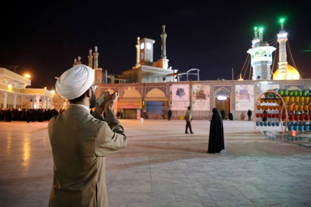Above, a cleric prays outside the Fatima Masumeh shrine in Iran’s holy city of Qom on March 16, 2020. (AFP file photo)