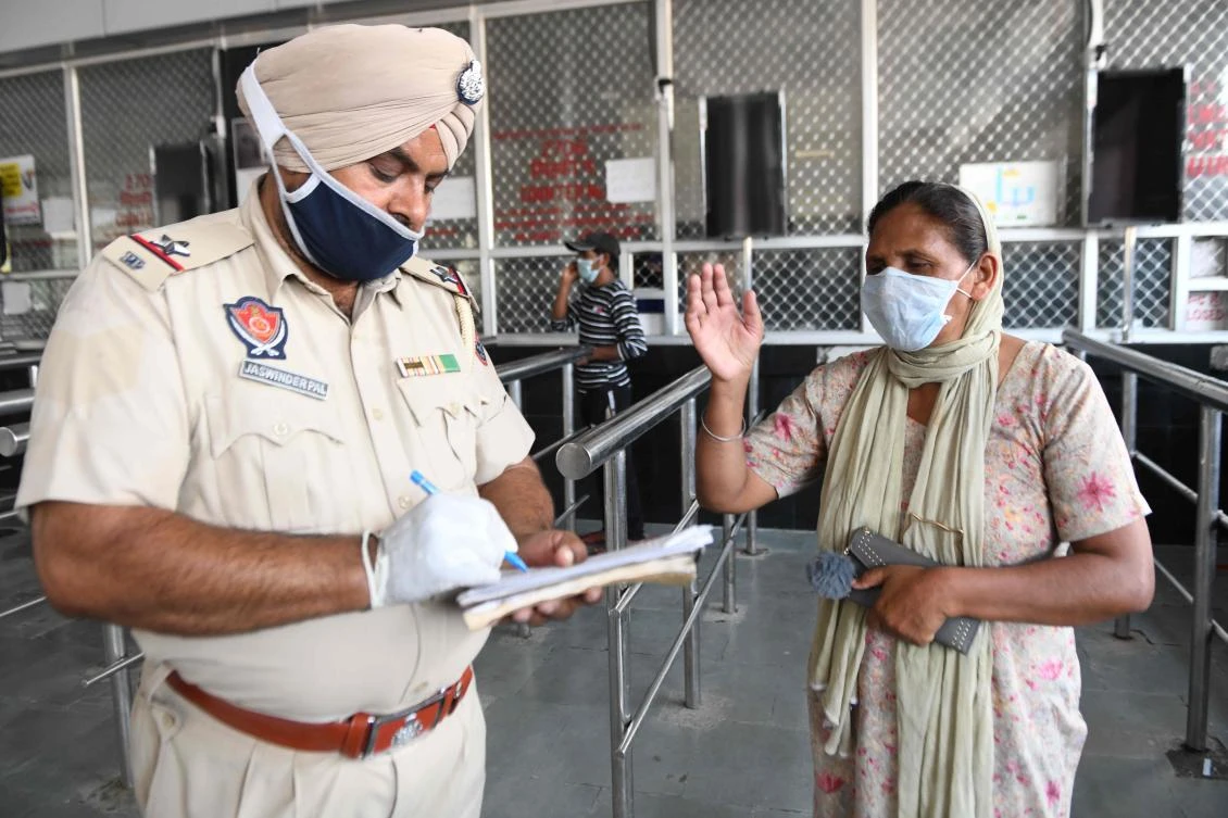 A police personnel helps a women to fill up forms for train ticket reservations at the Amritsar Railway Station after the government eased a nationwide lockdown on May 23, 2020. (AFP)
