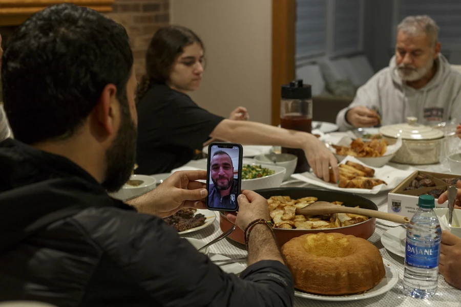Abbas Al Haj Ahmed talks with his cousin Adam Bazzi over a video call while their family eats at iftar. (File/AFP)