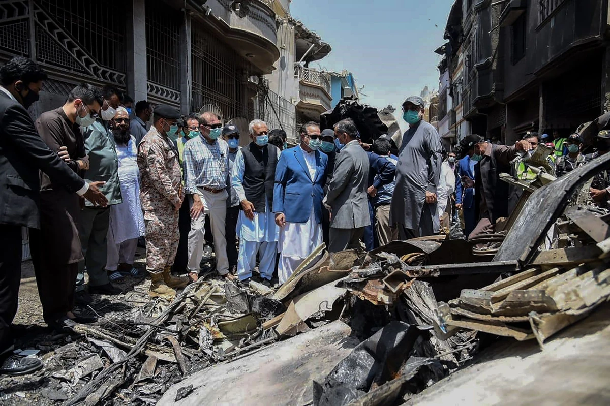 Pakistan's Aviation Minister Ghulam Sarwar Awana (C-L in black jacket) visits the crash site a day after a Pakistan International Airlines aircraft crashed in a residential area in Karachi. (AFP)