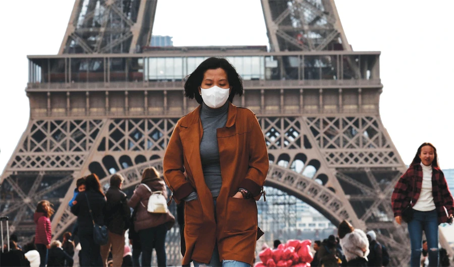 A woman wearing a mask walks in front of the Eiffel Tower, as the tourist industry in France has been badly affected by the coronavirus crisis. (Reuters)