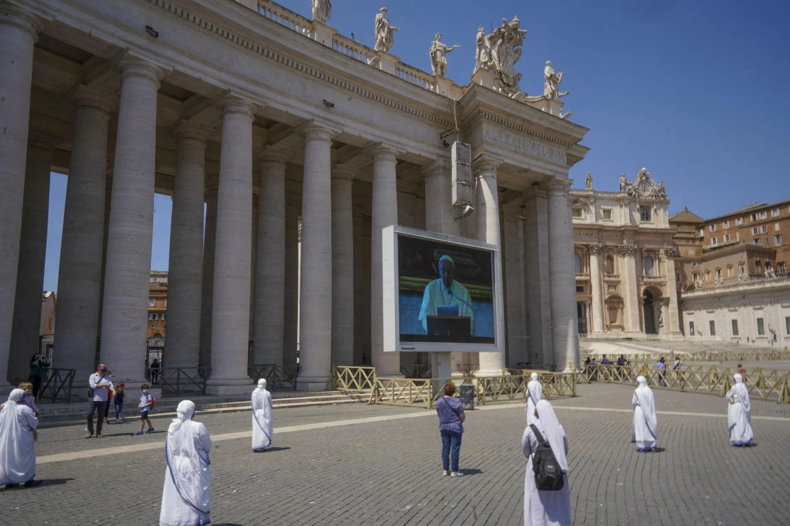 Nuns and faithful respecting social distancing look at Pope Francis reciting the Regina Coeli noon prayer on a giant screen in St. Peter’s Square on Sunday, May 24, 2020. (AP)