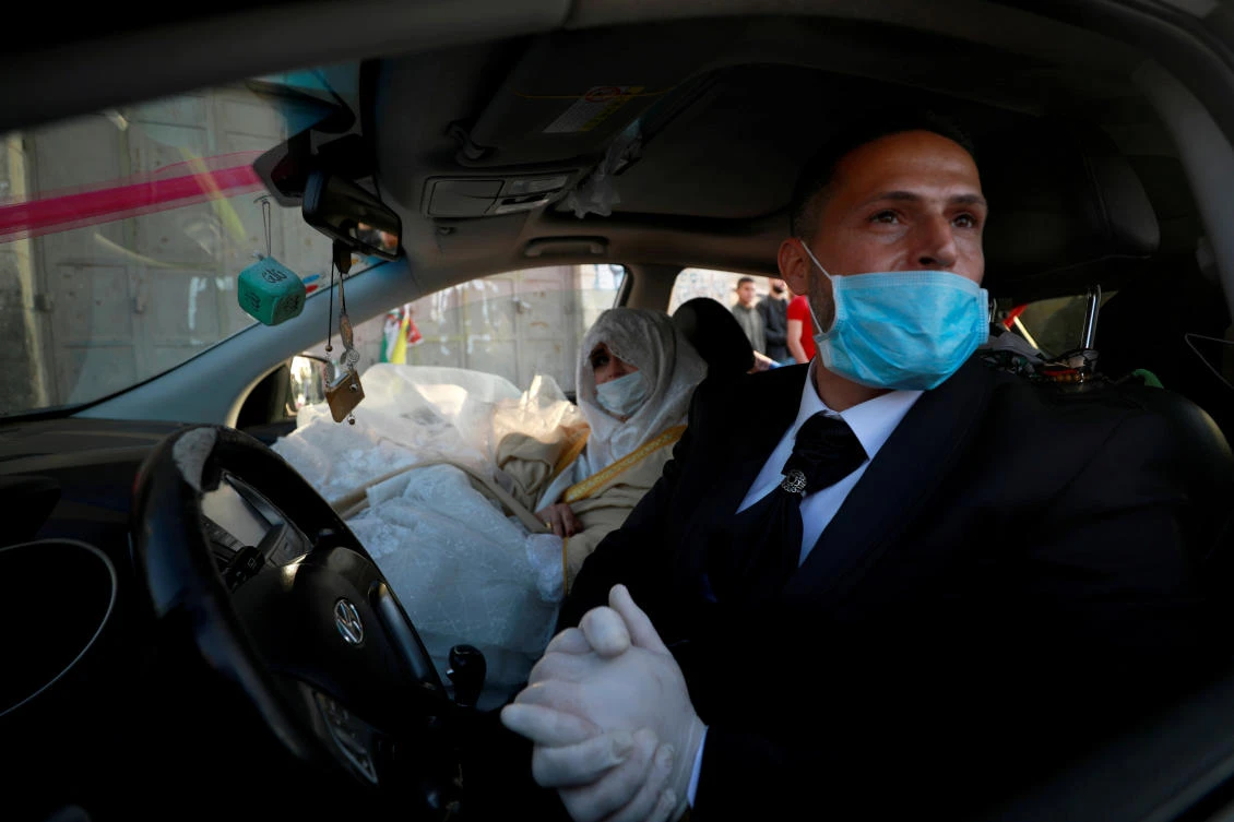 A Palestinian groom, Rafeh Qassim, wears a mask as he sits in a car with his bride on their wedding day amid concerns about the spread of the coronavirus disease (COVID-19), in Ramallah in the Israeli-occupied West Bank April 18, 2020. (Reuters)
