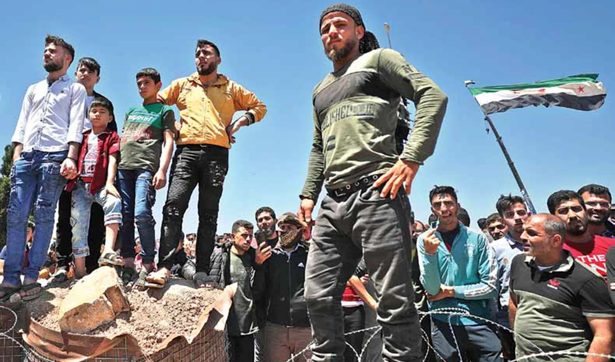 Syrians gather outside a Turkish army base near Idlib to demand the Turks fulfill their side of a truce agreement and allow them to return to their homes. (AFP)
