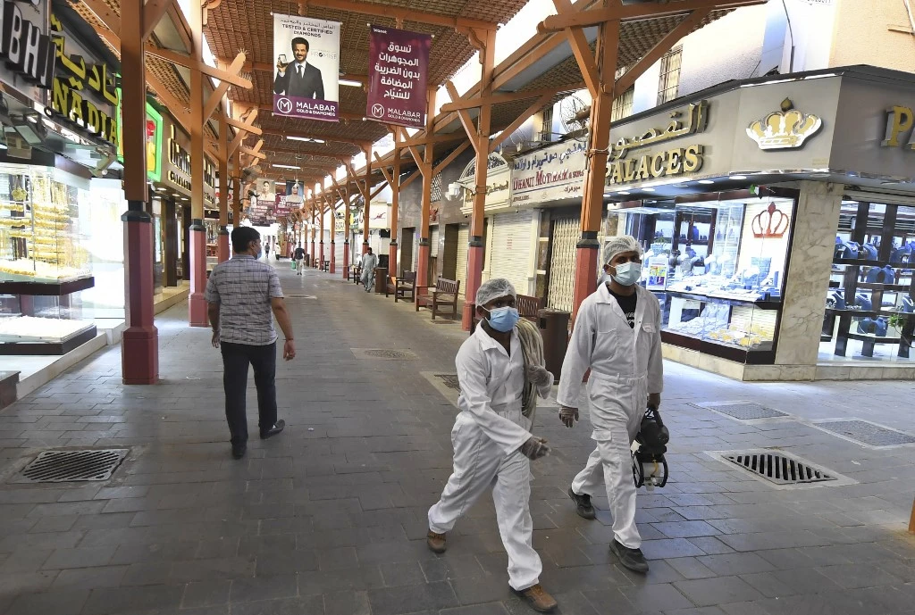Workers dressed in protective clothing and masks walk with sterilisation gear due to the COVID-19 coronavirus pandemic past jewellers' shops at the Dubai Gold Souk. (File/AFP)