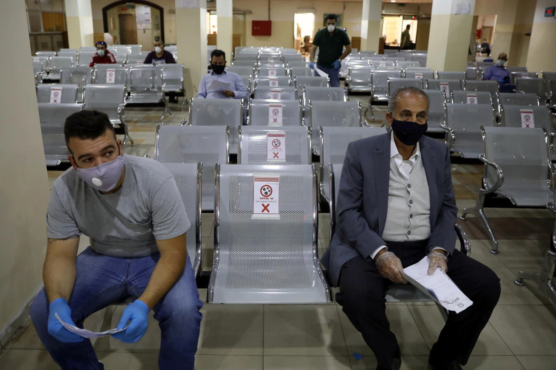 People wearing protective face masks wait to complete their transactions in the Civil Status Department after Jordan's public sector employees returned gradually to work, two months after they were ordered to stay home as part of a tight lockdown to stem the spread of the coronavirus disease (COVID-19), in Amman, Jordan May 26, 2020. (Reuters)