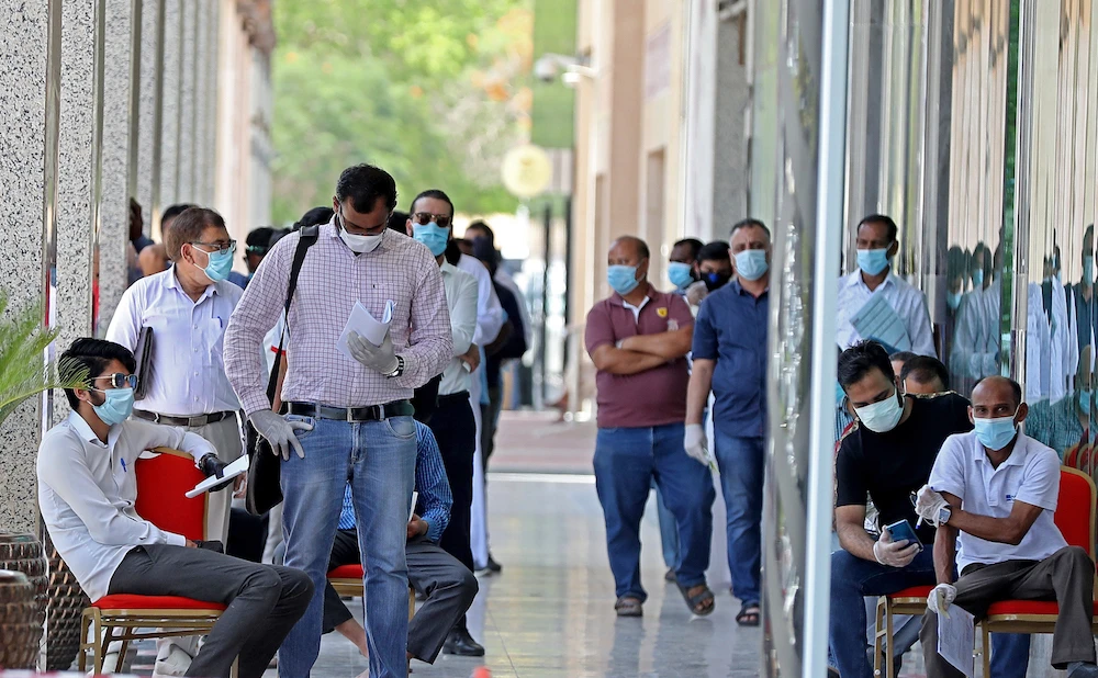 People wearing protective masks queue for services in Qatar’s capital Doha as the country begins enforcing the world’s toughest penalties for failing to wear masks in public while it battles one of the world’s highest coronavirus infection rates. (File/AFP)