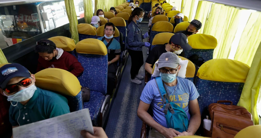 Overseas Filipino workers, who were quarantined as they arrived in the country weeks ago, wait inside a bus before they head back to their provinces on Tuesday. (AP)