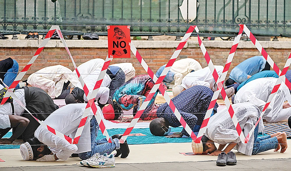 Signs indicating social distancing restriction measures to prevent the spread of coronavirus disease are seen while Muslims attend Eid Al-Fitr prayer at Piazza Vittorio Square, Rome. (AP)
