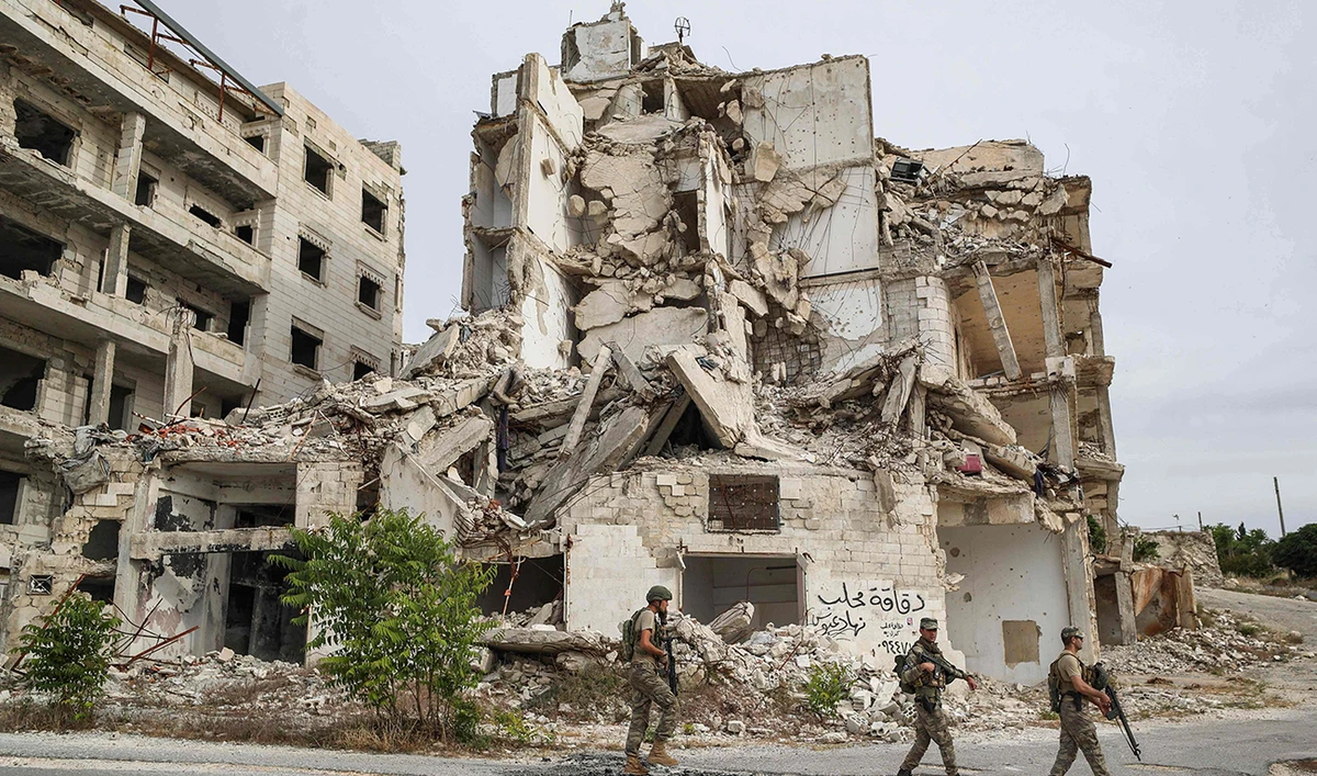 Turkish soldiers patrol along a road past destroyed buildings atop the Arbaeen hill overlooking Ariha in the southern countryside of Syria’s Idlib province. (AFP)