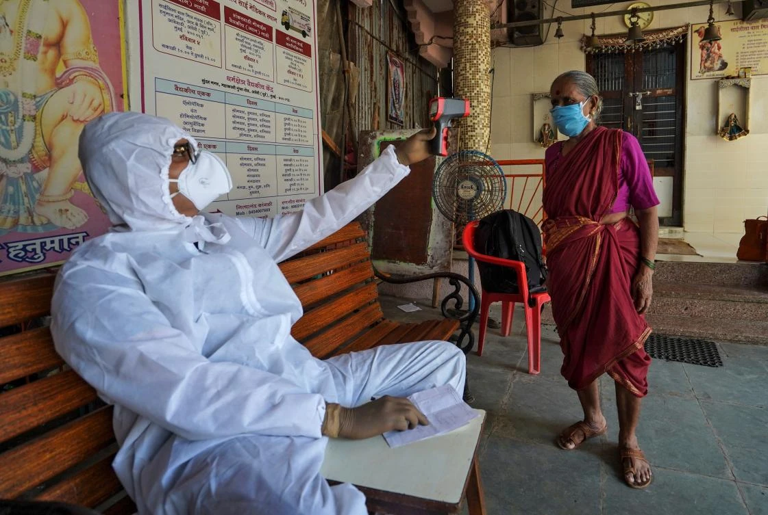 Sanjay Meriya, also known as the Spindoctor, checks the temperature of a woman in a temporary health center in Mumbai, India on May 25, 2020. (AFP)