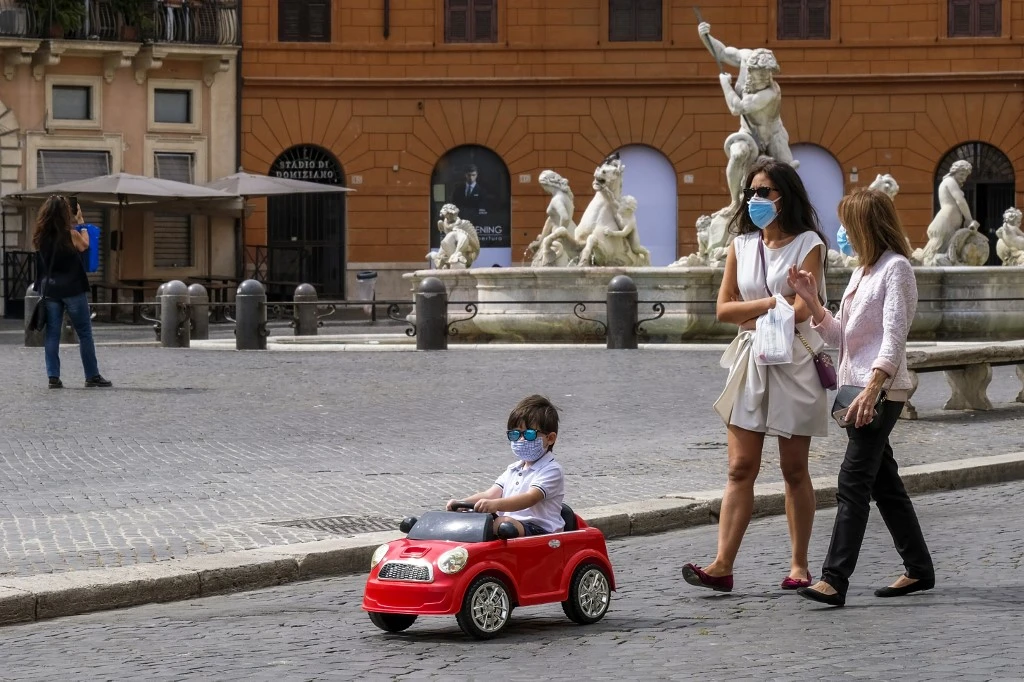 The global community is taking measured steps towards a post-coronavirus normalcy. Above, a boy wearing a face mask drives a toy car across Piazza Navona in Rome on May 28, 2020. (AFP)