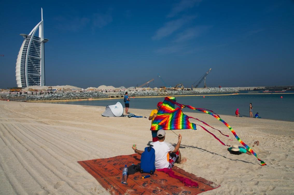 A young boy prepares to fly a kite on a public beach with the Burj Al-Arab hotel behind him in Dubai, United Arab Emirates, Friday, May 29, 2020. (AP/Jon Gambrell)