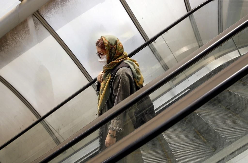 An Iranian woman, wearing a protective face mask, uses an escalator in the capital city of Tehran. (AFP)
