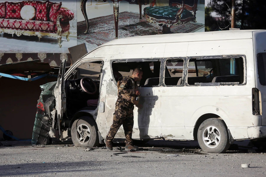 An Afghan security forces member inspects a bus carrying local TV station employees that hit a roadside bomb in Kabul, Afghanistan, Saturday, May 30, 2020. (AP/Rahmat Gul)