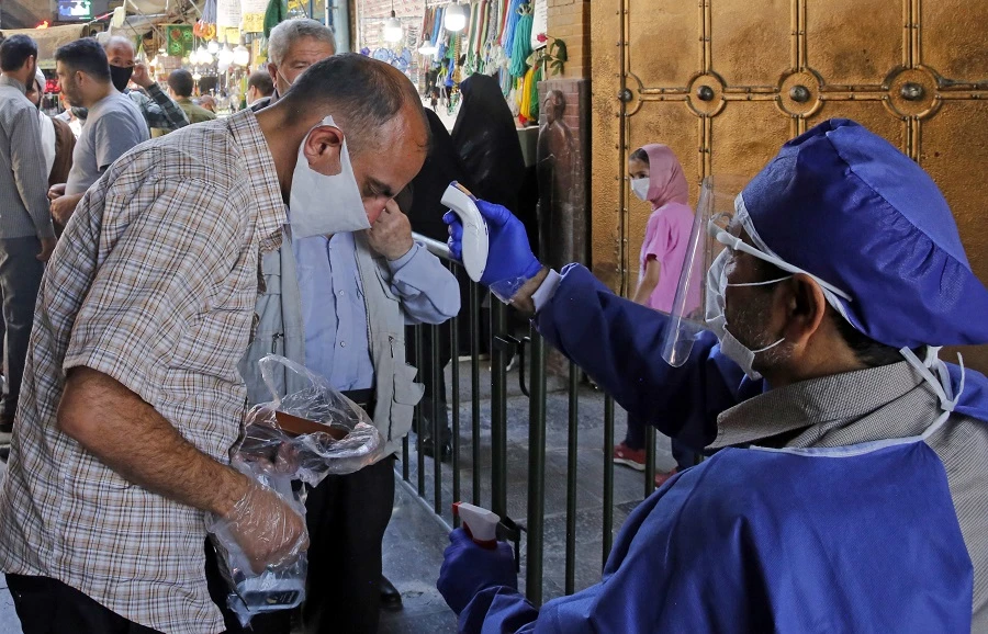 An Iranian official checks the temperature of visitors at the Shah Abdol-Azim shrine in the capital Tehran on May 25, 2020, following the reopening of major Shiite shrines across the Islamic republic, more than two months after they were closed because of the Middle East's deadliest novel coronavirus outbreak. (File/AFP)
