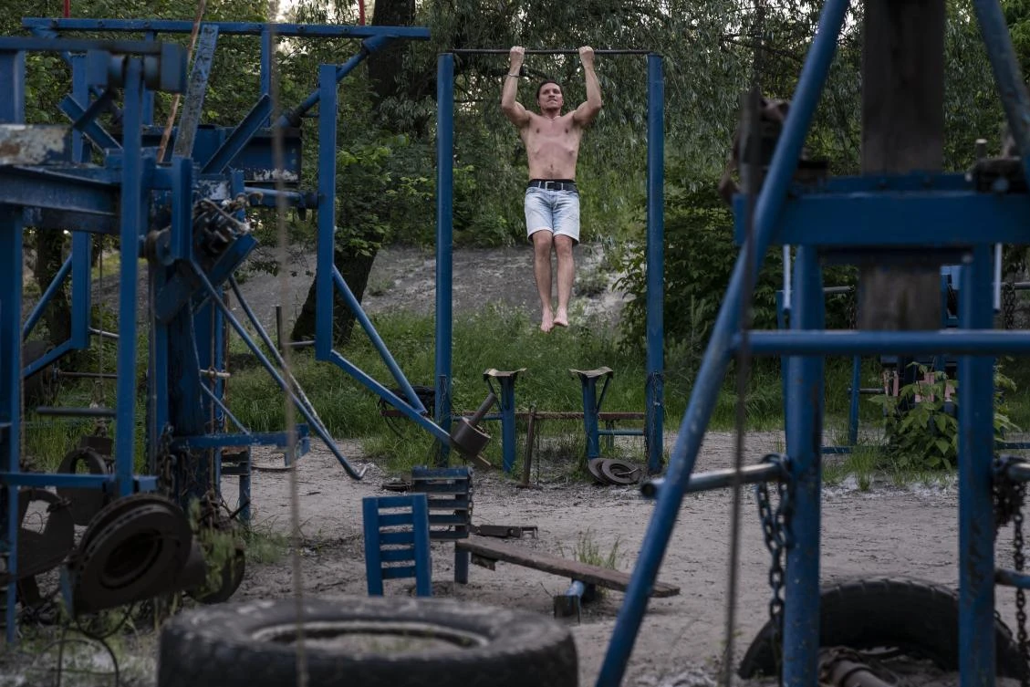 In this photo taken on Sunday, June 7, 2020, a man trains in the outdoors gym on the Dolobetskiy island on the Dnipro River in Kyiv, Ukraine. Relishing an opportunity to do exercise after a long lockdown, hundreds of Kyiv residents flock to an improvised outdoor workout on an island facing the Ukrainian capital. The Kachalka gym on the Dolobetskiy island on the Dnipro river has enjoyed broad popularity ever since it opened in 1966. (AP Photo/Evgeniy Maloletka)