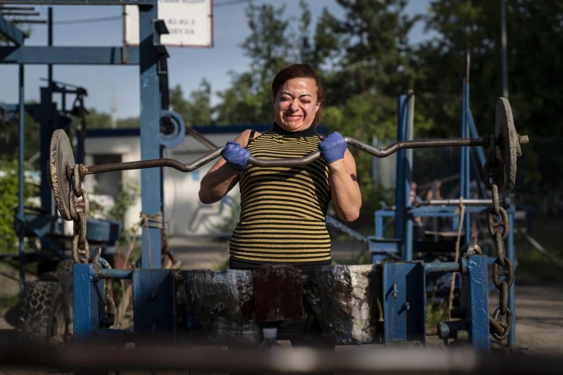 In this photo taken on Saturday, June 6, 2020, a woman trains in the outdoors gym on the Dolobetskiy island on the Dnipro River in Kyiv, Ukraine. Relishing an opportunity to do exercise after a long lockdown, hundreds of Kyiv residents flock to an improvised outdoor workout on an island facing the Ukrainian capital. The Kachalka gym on the Dolobetskiy island on the Dnipro river has enjoyed broad popularity ever since it opened in 1966. (AP Photo/Evgeniy Maloletka)