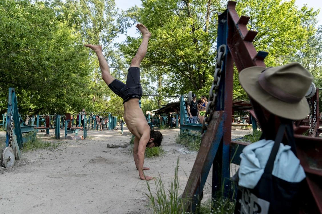 In this photo taken on Saturday, June 6, 2020, a man trains in the outdoors gym on on the Dolobetskiy island on the Dnipro River in Kyiv, Ukraine. Relishing an opportunity to do exercise after a long lockdown, hundreds of Kyiv residents flock to an improvised outdoor workout on an island facing the Ukrainian capital. The Kachalka gym on the Dolobetskiy island on the Dnipro river has enjoyed broad popularity ever since it opened in 1966. (AP Photo/Evgeniy Maloletka)