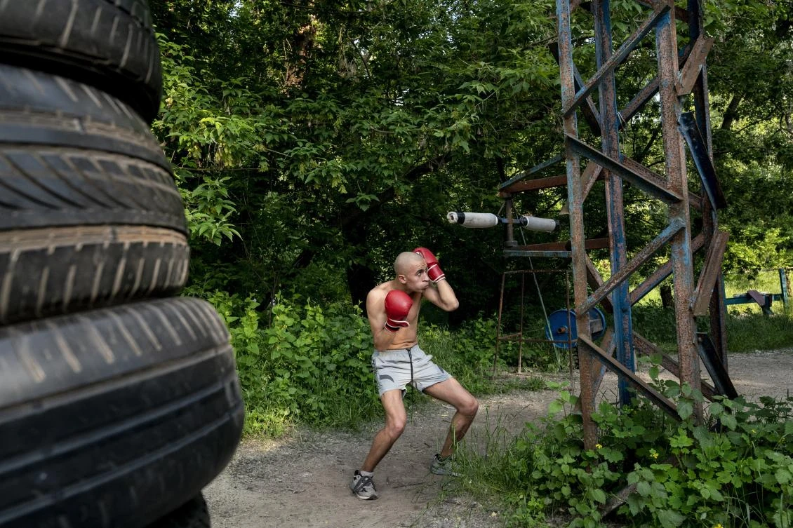 In this photo taken on Saturday, June 6, 2020, a man trains to box in the outdoors gym on the Dolobetskiy island on the Dnipro River in Kyiv, Ukraine. Relishing an opportunity to do exercise after a long lockdown, hundreds of Kyiv residents flock to an improvised outdoor workout on an island facing the Ukrainian capital. The Kachalka gym on the Dolobetskiy island on the Dnipro river has enjoyed broad popularity ever since it opened in 1966. (AP Photo/Evgeniy Maloletka)