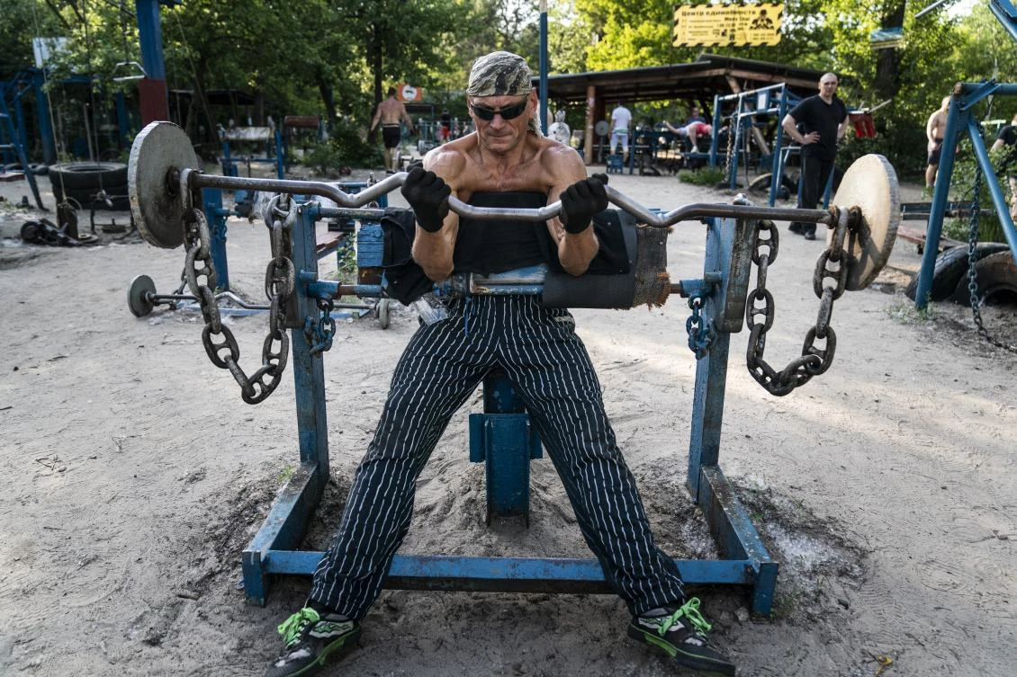 In this photo taken on Saturday, June 6, 2020, Andriy Demyanchenko prepares to lift weight in the outdoors gym on the Dolobetskiy island on the Dnipro River in Kyiv, Ukraine. Relishing an opportunity to do exercise after a long lockdown, hundreds of Kyiv residents flock to an improvised outdoor workout on an island facing the Ukrainian capital. The Kachalka gym on the Dolobetskiy island on the Dnipro river has enjoyed broad popularity ever since it opened in 1966. (AP Photo/Evgeniy Maloletka)