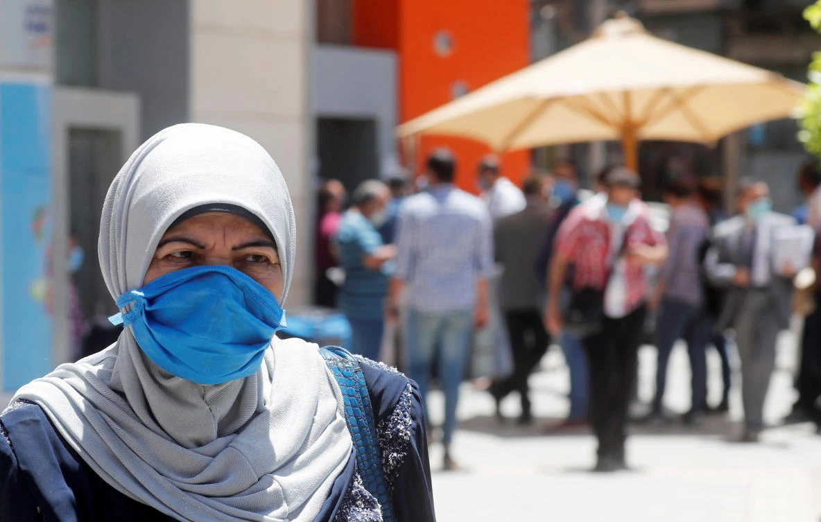 A woman wearing a protective mask looks on as people wait to make withdrawals outside a branch of Commercial International Bank (CIB), amid concerns over the coronavirus disease (COVID-19) in Cairo, Egypt May 31, 2020. Picture taken May 31, 2020. (Reuters)