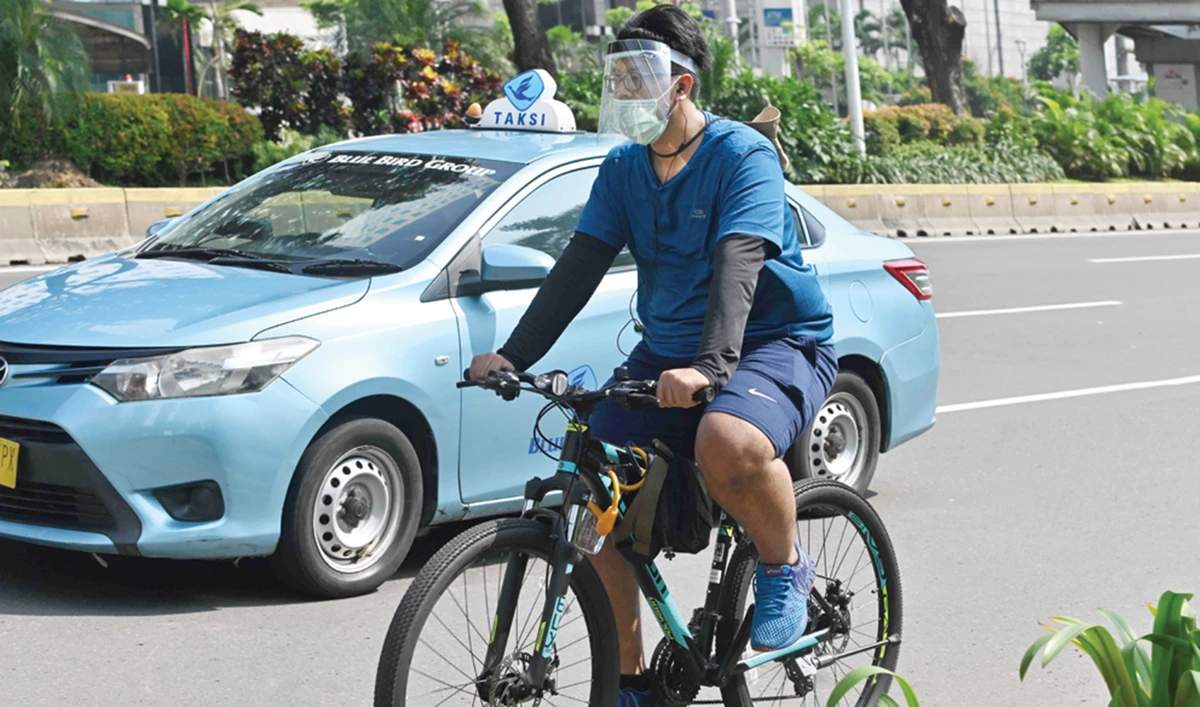 An Indonesian man wearing a face mask and a face shield enjoys the partial lockdown, on his bicycle in Jakarta on Monday. (AFP)