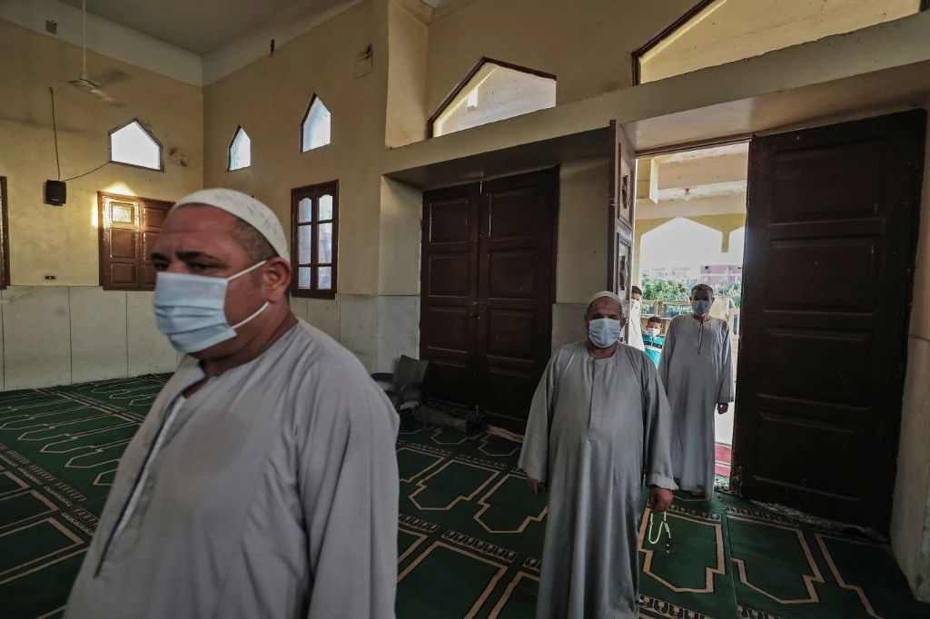 Workers of a local mosque in the village of Shamma in Egypt's northern Nile delta province of Menoufia enter inside while clad in masks due to the COVID-19 pandemic. (File/AFP)