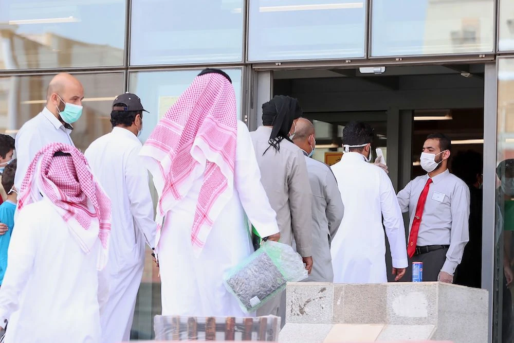 Customers queue for a temperature check before entering a mobile shop in Makkah. (AFP)