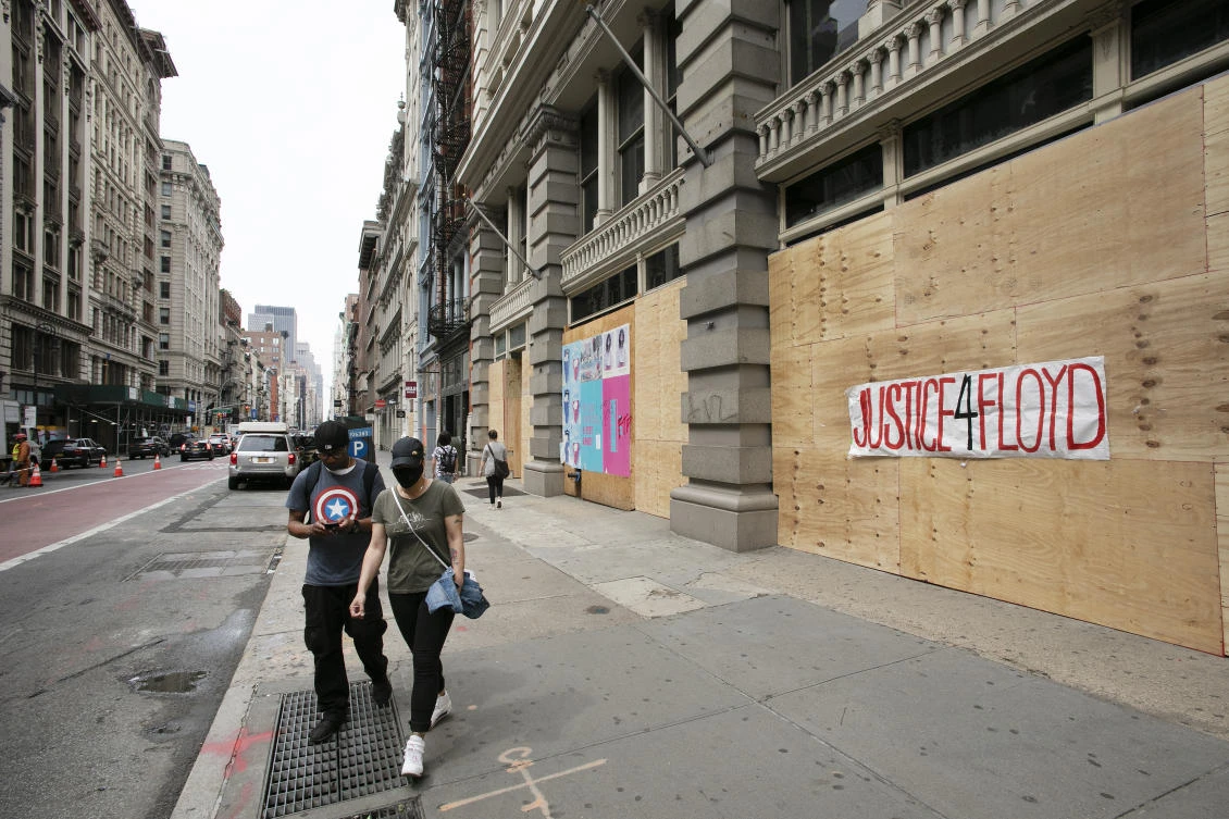 Pedestrians pass a boarded up storefront, Wednesday, June 3, 2020, in the SoHo neighborhood of New York. Graffiti on the boarded up store reads ‘Justice 4 Floyd.’ (AP Photo)