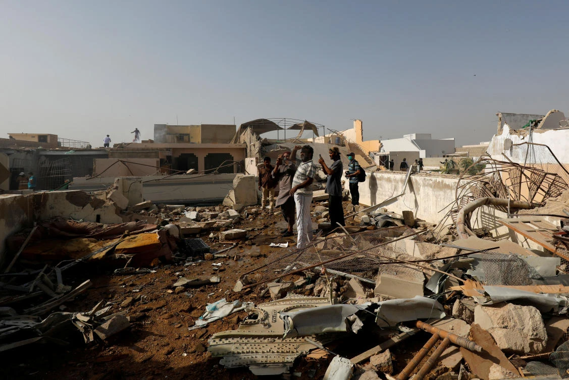 People stand on a roof of a house amidst debris of a passenger plane, crashed in a residential area near an airport in Karachi, Pakistan May 22, 2020. (Reuters)
