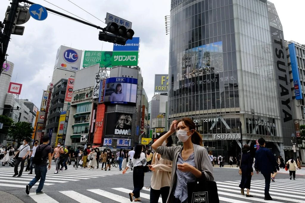 Tokyo recently began to ease restrictions put in place to prevent the spread of the coronavirus. Above, people wearing face masks walk across the Shibuya Crossing in Tokyo. (AFP file photo)