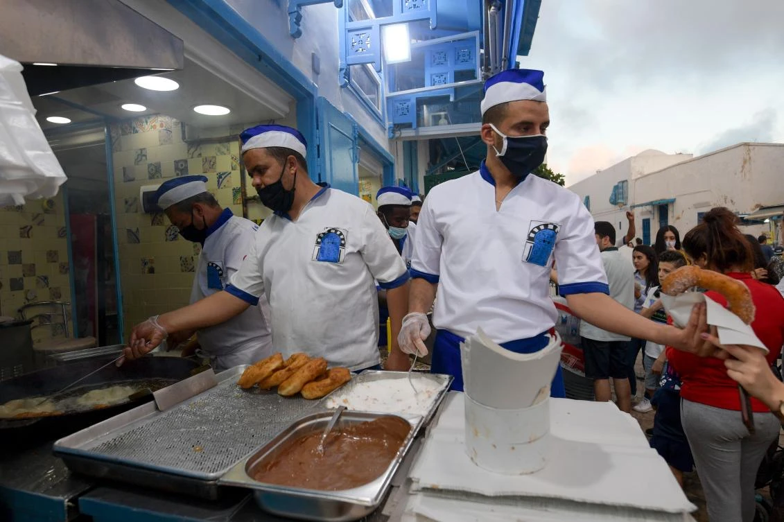 Tunisians cooks sell a local version of the donut in the village of Sidi Bou Said, some 20 kilometers northeast of Tunis, on May 30, 2020, after shops reopened following a 3 month shutdown. (AFP)