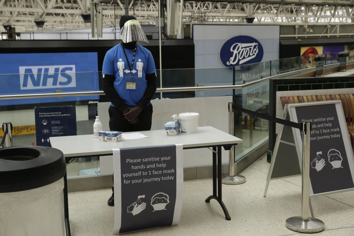 A member of staff stands ready to give out face masks and offer hand sanitiser to help stop the spread of coronavirus at Waterloo station in London, Thursday, June 4, 2020. (AP)
