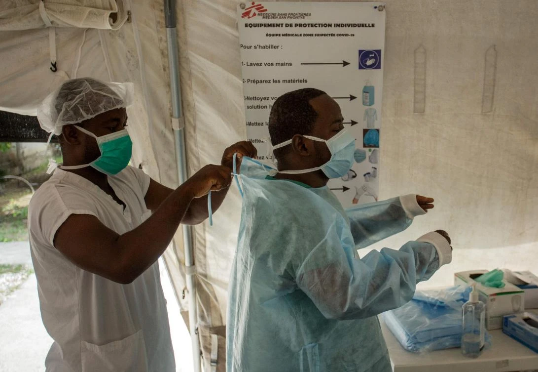 Dr. Erneau Mondesir (R), member of the staff of the Doctors Without Borders Drouillard Hospital in Cite Soleil, Haiti, puts on his personal protective equipment on June 3, 2020. (AFP)