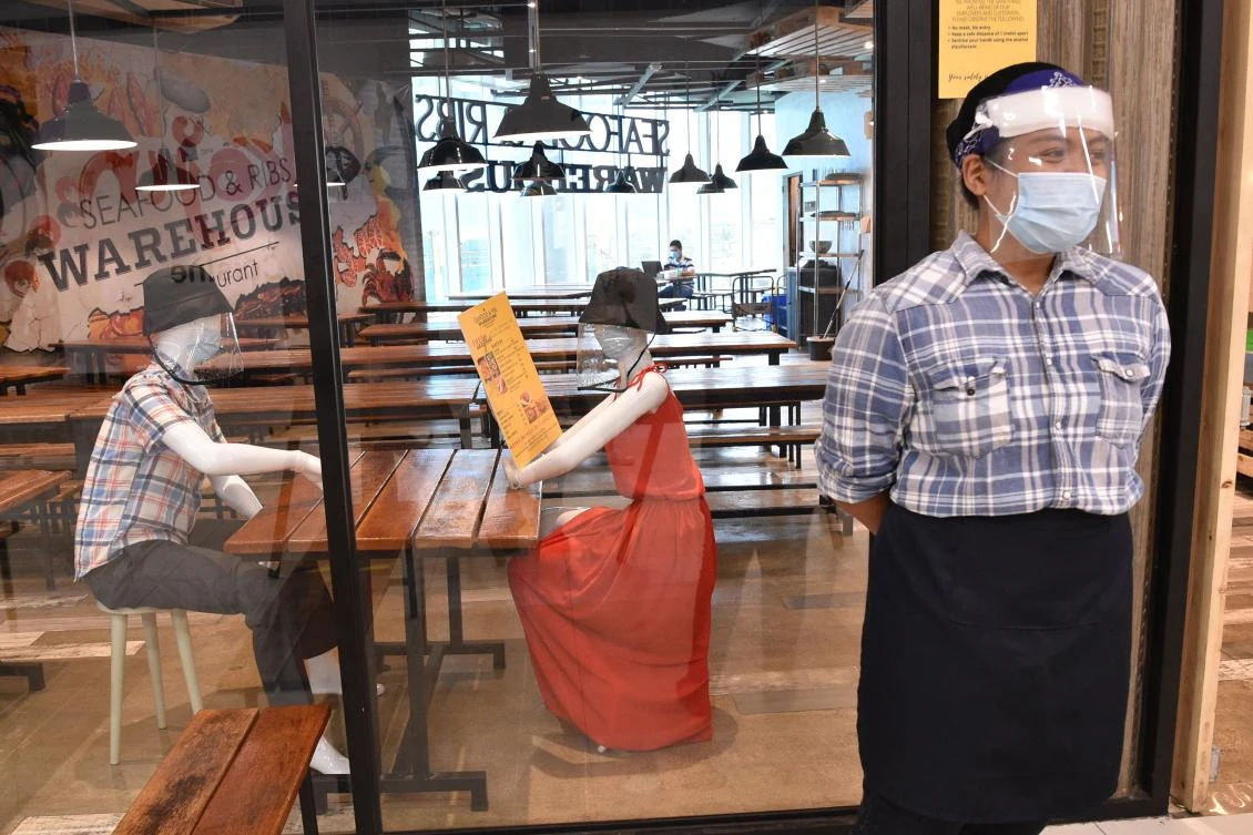 A restaurant staff stands near mannequins that simulate seating arrangements at restaurant in a mall in Manila on June 2, 2020. (AFP)