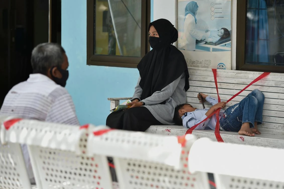 People wait at a seating area, with some seats marked off for social distancing amid the COVID-19 coronavirus pandemic, at a community health center in Samahani, Aceh province on June 5, 2020. (AFP)