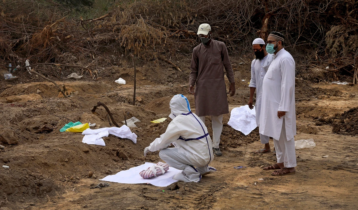 The body of a prematurely born one week old baby of a covid positive mother being prepared for burial at the designated burial spot for covid patients in New Delhi on June 5, 2020. (AP)