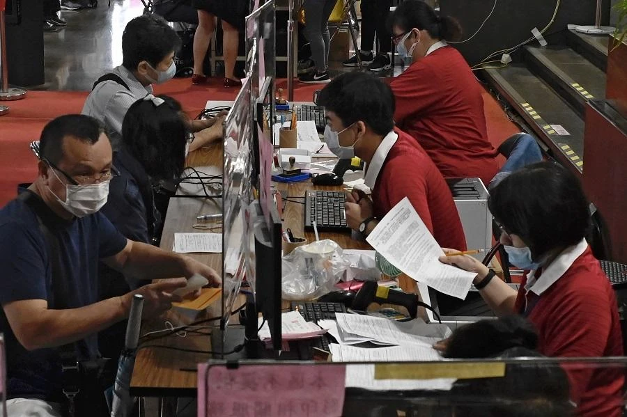 Employees (R-in red) wearing face masks due the COVID-19 pandemic sit behind plastic partitions as they check tax documents submitted by local residents (L) at the Taipei National Taxation Bureau in Taipei on May 12, 2020. (File/AFP)