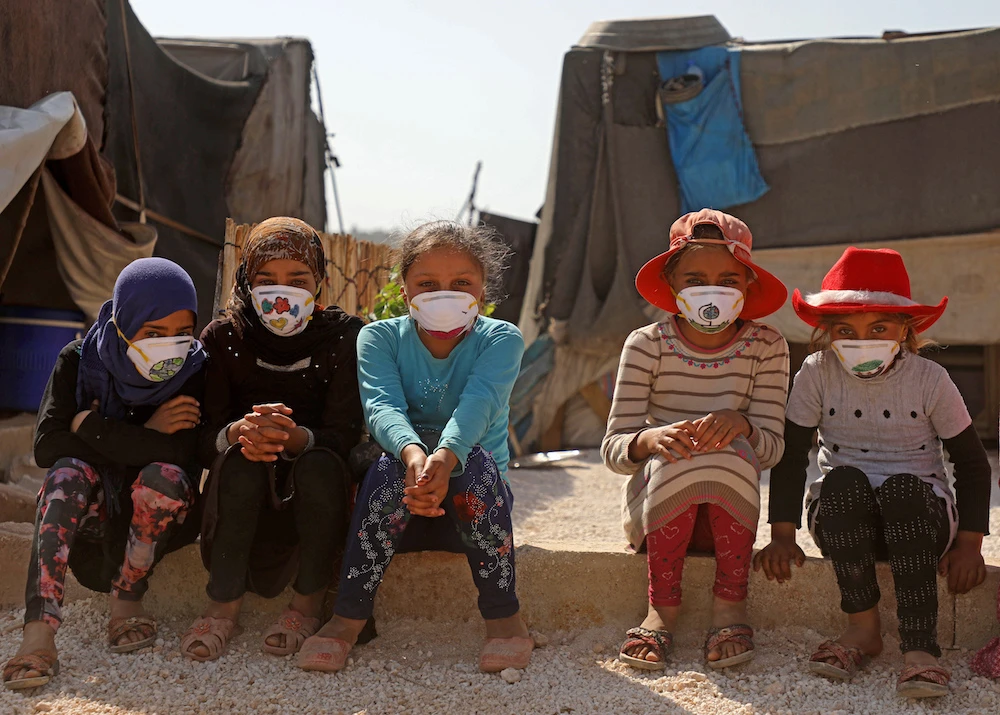 Displaced Syrian girls wear face masks decorated by artists during a COVID-19 awareness campaign at the Bardaqli camp in the town of Dana in Syria's northwestern Idlib province, on April 20, 2020. (AFP/File Photo)