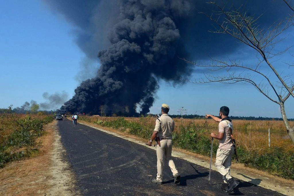Policemen ask people to move to a safer place as smoke rises to the sky following an explosion at an Oil India Limited well in Baghjan, northeast Indian state of Assam on June 9, 2020. (AFP)
