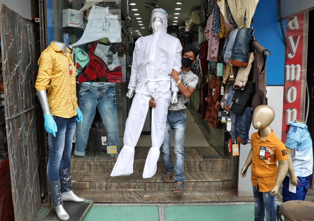 A worker carries a mannequin wearing protective gear for display outside a garment shop in Kolkata, India, June 10, 2020. (Reuters)