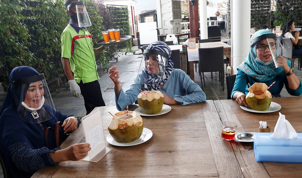 Customers wearing protective face shields to help curb the spread of coronavirus enjoy lunch at a seafood restaurant on the outskirts of Jakarta on Wednesday. (AP)